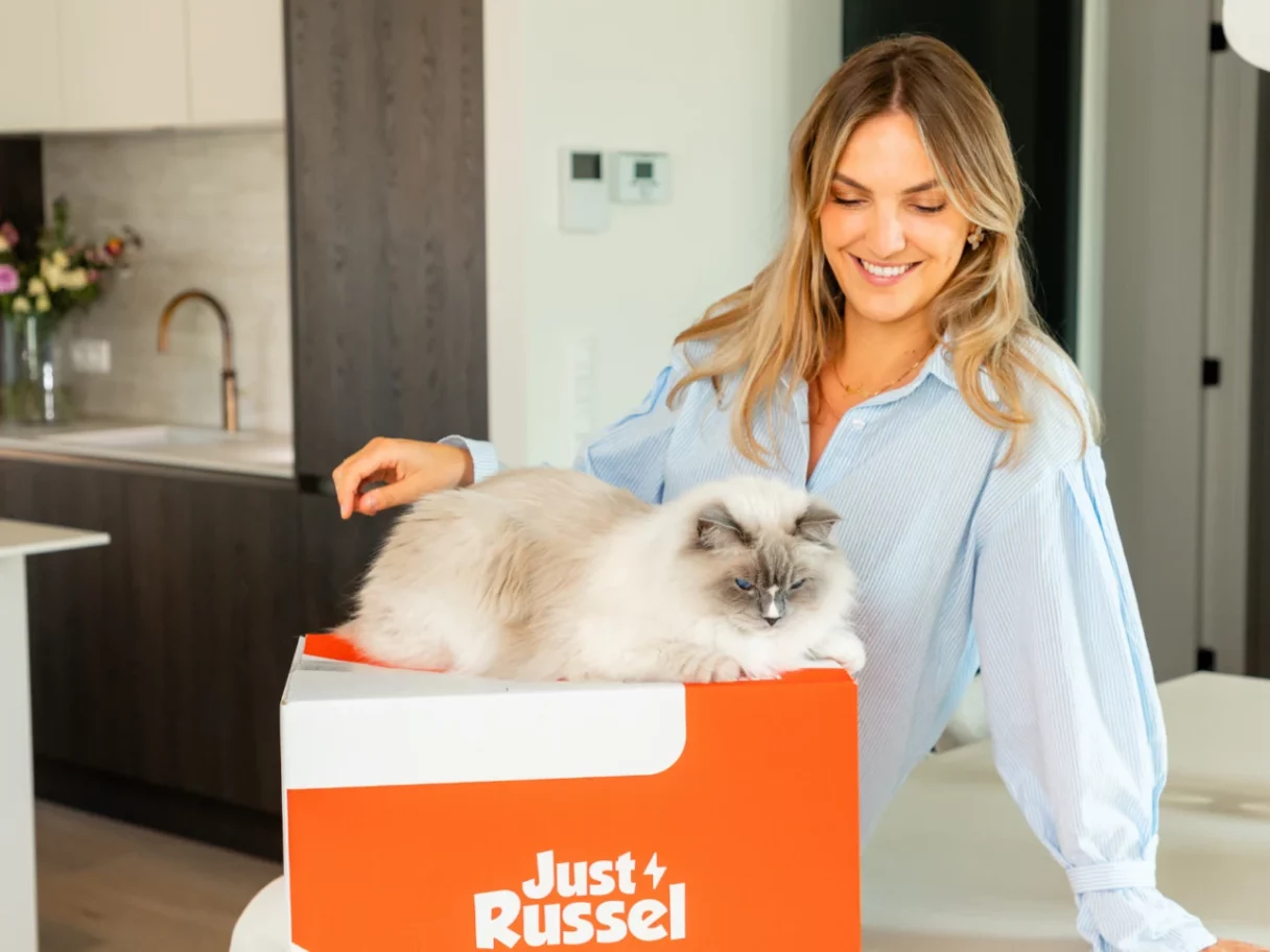 Frau steht neben einer Just Russel Box, auf der eine Katze entspannt liegt.