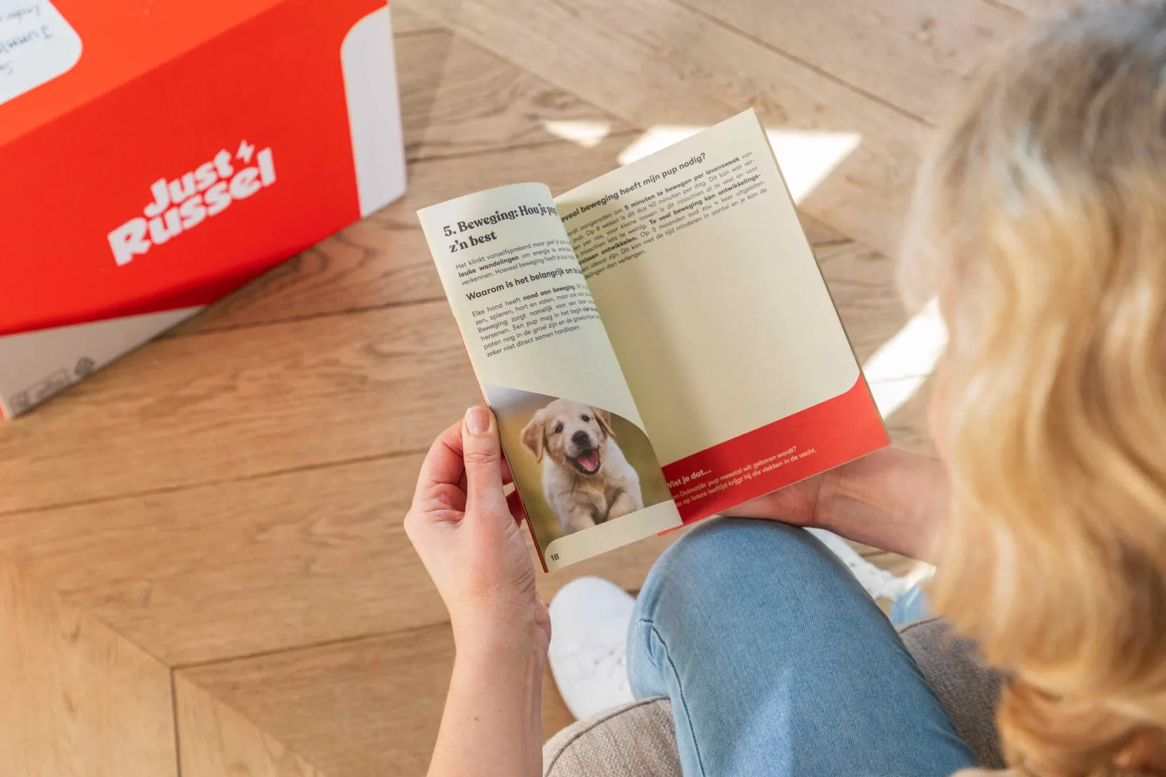 Eine frisch gebackene Hundemama liest im Welpenratgeber von Just Russel über Tipps zur richtigen Pflege und Erziehung ihres Welpen.