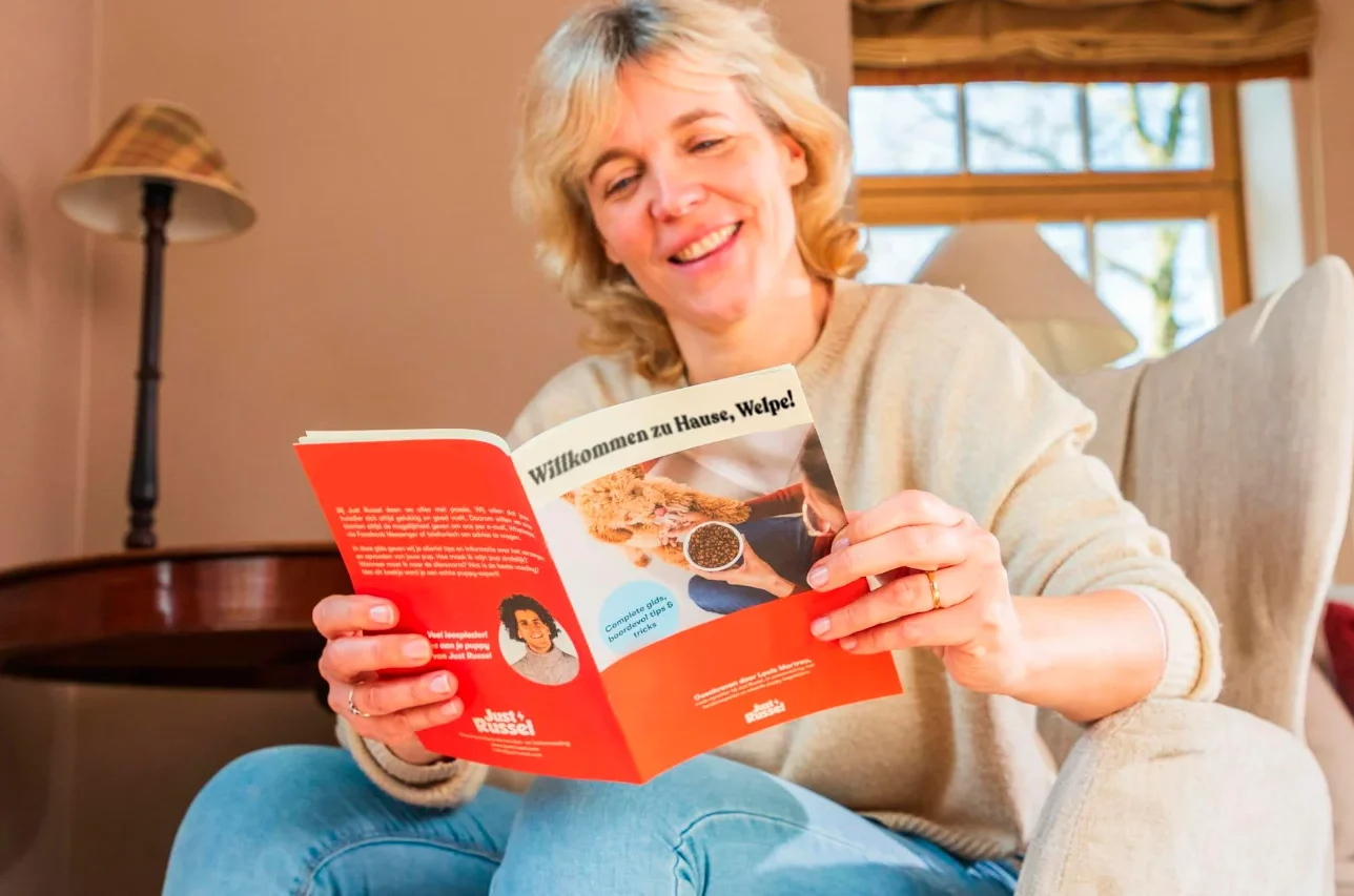 Frau liest ein Just Russel Heft mit Informationen zur Welpenernährung.