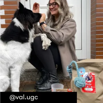 Just Russel Kundin präsentiert mit ihrem schwarz weißen Hund ein Kunststück und zeigt dabei ihre Lieferung.